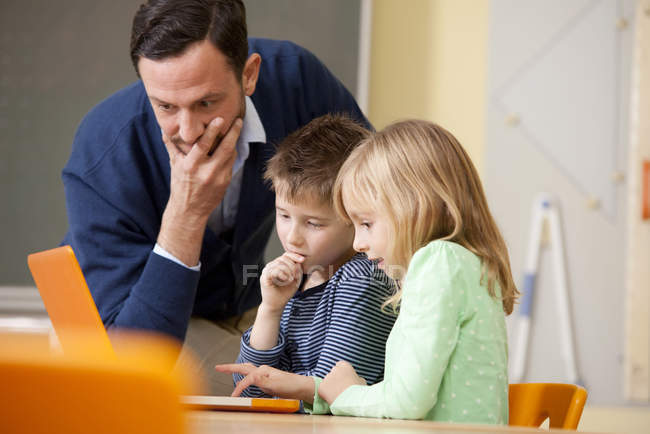 Teacher with pupils using laptop in classroom — Stock Photo
