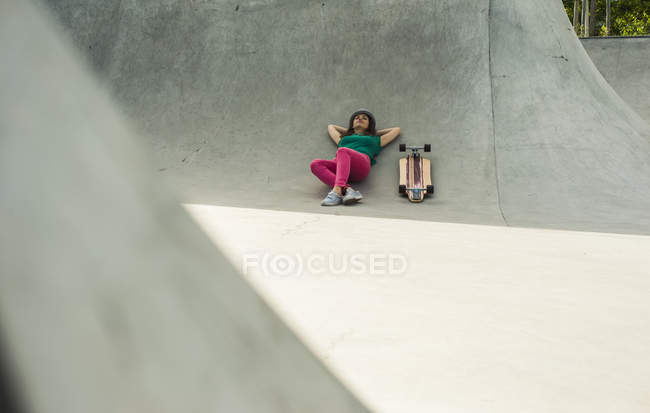 Woman lying next to skateboard — Stock Photo
