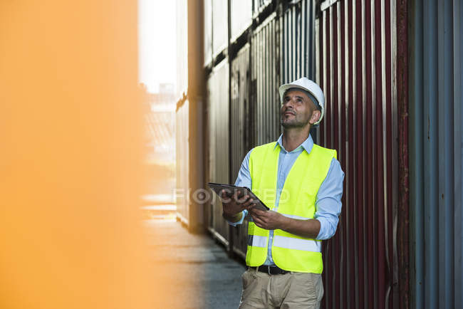 Homme avec tablette numérique portant un gilet réfléchissant au port du conteneur — Photo de stock