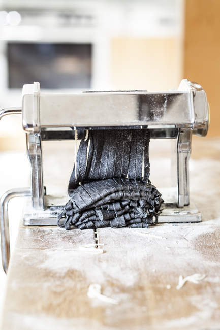 Fabrication de tagliatelles noires dans une machine à pâtes — Photo de stock
