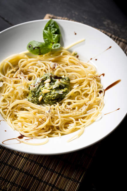 Plate of spaghetti with pesto Genovese and fresh basil leaves, top view — Stock Photo