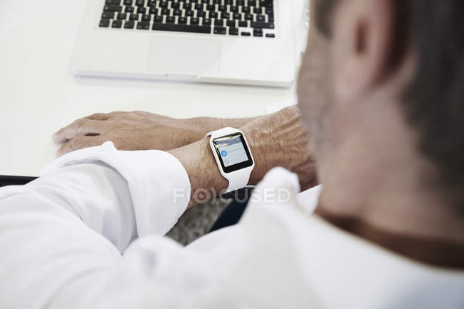 Uomo d'affari in ufficio guardando smartwatch — Foto stock