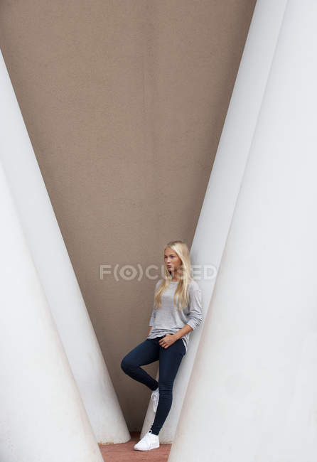 Portrait of blond female teenager leaning on concrete column — Stock Photo