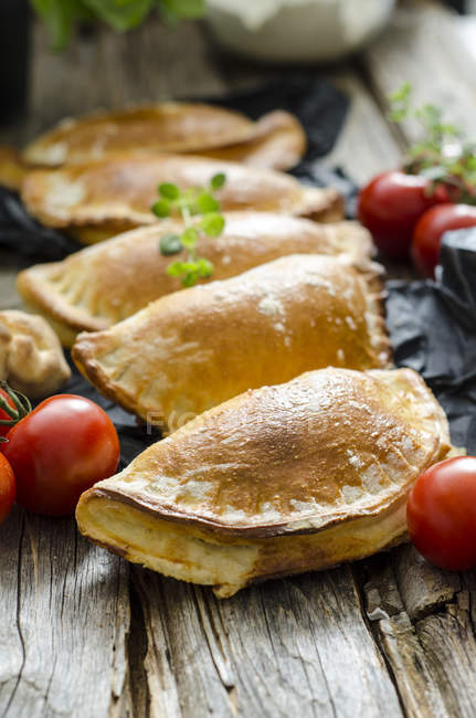 Closeup of calzone stuffed with tomatoes and sage on wood — Stock Photo
