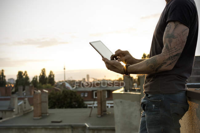 Alemania, Berlín, Hombre maduro en la terraza de la azotea con tableta digital - foto de stock