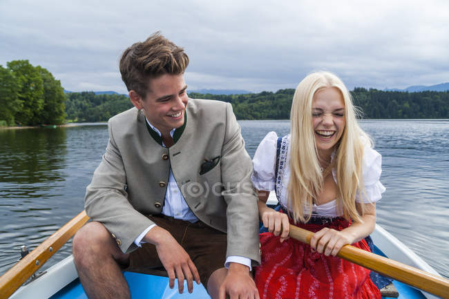 Allemagne, Bavière, jeune couple vêtu de vêtements traditionnels assis dans un bateau à rames sur Staffelsee — Photo de stock