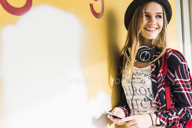 Smiling teenage girl leaning against wall — Stock Photo