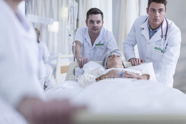 Персонал лікарні, штовхаючи ліжко з неправдивими пацієнтки — стокове фото