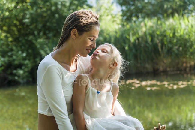 Fille embrasser mère à un lac — Photo de stock