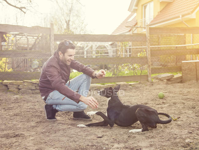 Uomo che allena il suo cane in cortile — Foto stock
