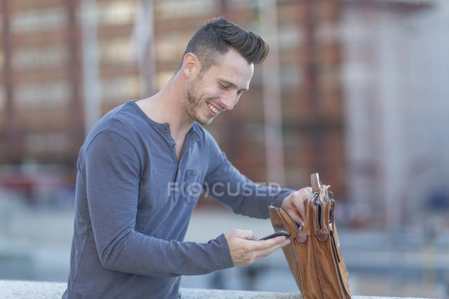 Hombre en la ciudad con maletín y celular - foto de stock