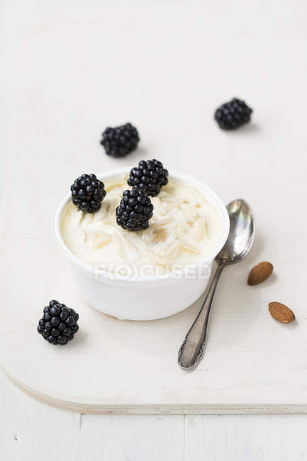 Almond ice cream with blackberries with spoon on table — Stock Photo