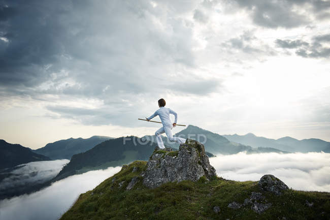 Austria, Kranzhorn, Mid donna adulta che si allena con il bastone da combattimento sulla cima della montagna — Foto stock