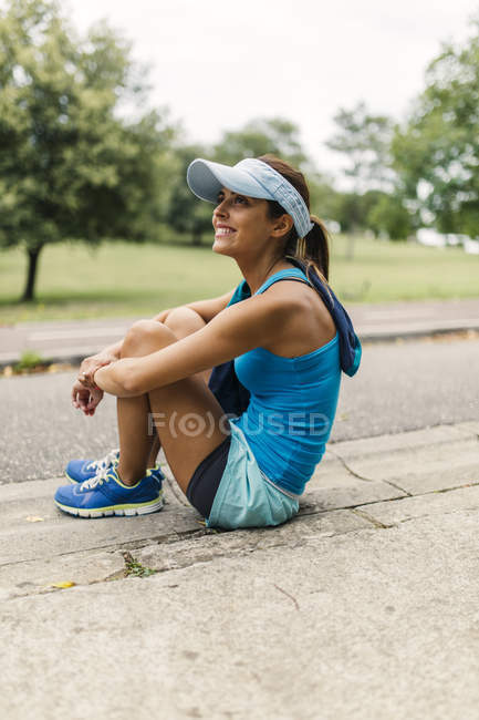 Young female athlete sitting on ground, taking a break — Stock Photo