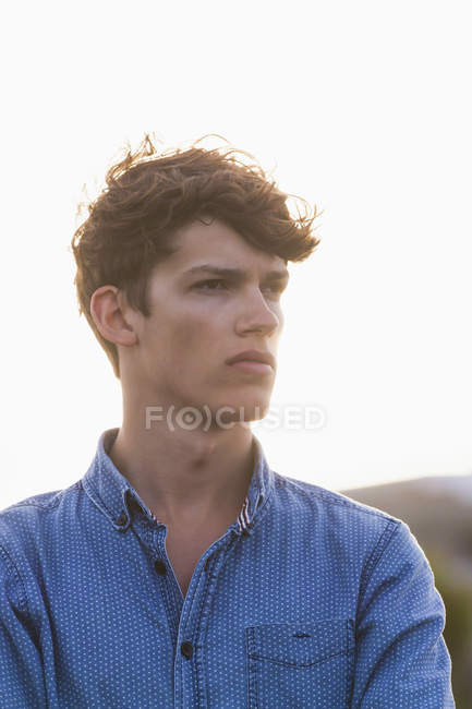 Portrait of serious looking young man at backlight — Stock Photo