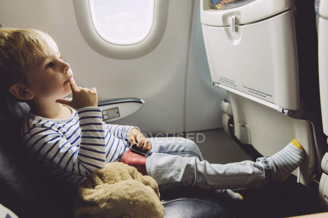 Страшный маленький мальчик, сидящий в самолете — стоковое фото