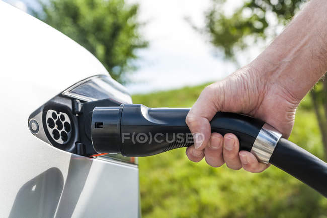 Charging of an electric car, closeup of male hand — Stock Photo