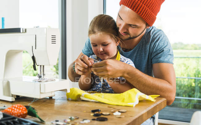 Padre e figlia a casa utilizzando la macchina da cucire — Foto stock