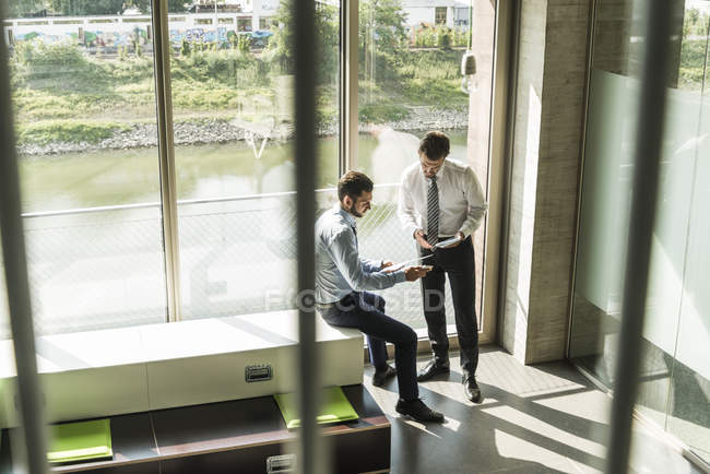 Deux jeunes hommes d'affaires regardant document et tablette numérique — Photo de stock