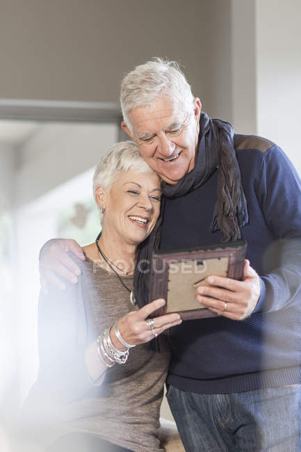 Coppia anziana guardando insieme a cornice — Foto stock
