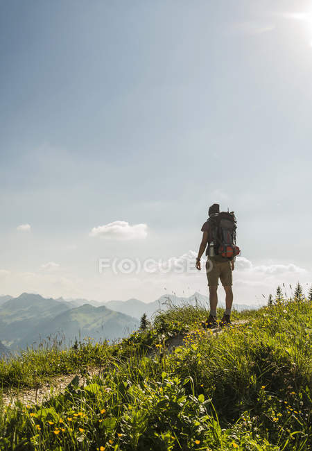 Austria, Tirol, Tannheimer Tal, joven de pie en el sendero de montaña mirando a la vista - foto de stock