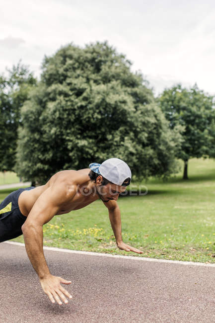 Jeune homme athlétique faisant de l'exercice dans le parc — Photo de stock