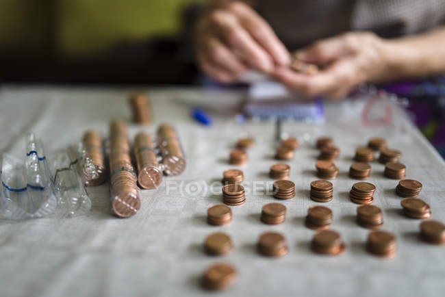Old woman counting money, making stacks of Euro cents — Stock Photo