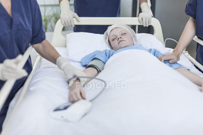 Fille couchée dans le lit d'hôpital avec des chirurgiens autour — Photo de stock