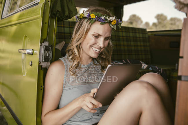 Happy young woman looking at tablet computer in van — Stock Photo