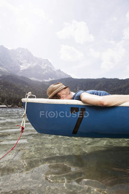 Homme couché en bateau à rames sur le lac — Photo de stock