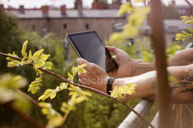Alemania, Berlín, Hombre sosteniendo la tableta digital en el balcón - foto de stock