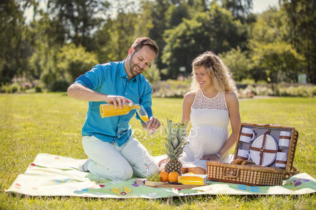 Happy couple having a picnic in park, pregnant woman — Stock Photo