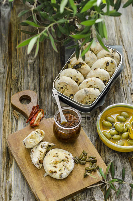 Pesto de tomates avec des petits pains d'olives et de tomates faits maison sur une planche de bois — Photo de stock