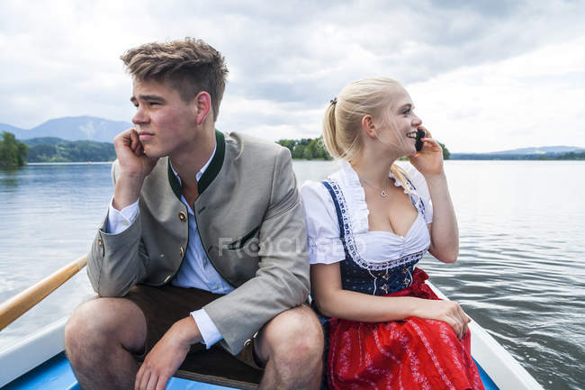 Allemagne, Bavière, jeune couple vêtu de vêtements traditionnels assis dans un bateau à rames sur Staffelsee — Photo de stock