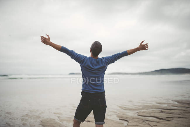 Spain, Galicia, Ferrol, man on the beach with outstretched arms — Stock Photo