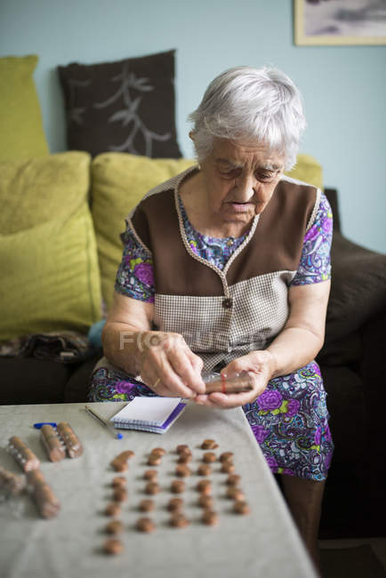 Seniorin sitzt zu Hause auf Couch und zählt Eurocent-Münzen — Stockfoto