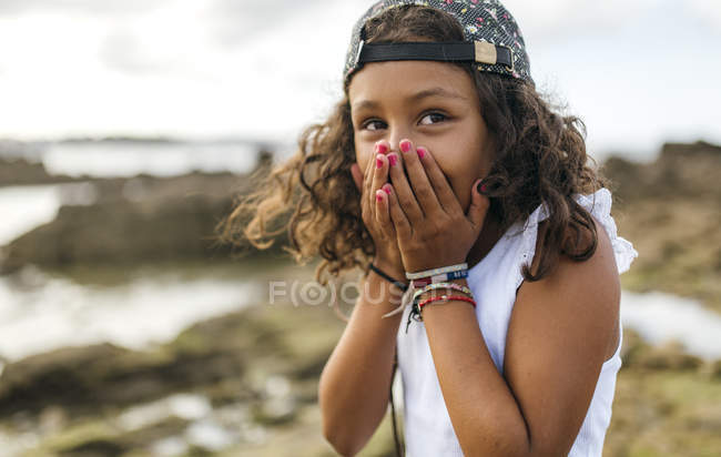 Portrait of little girl covering mouth with her hands — Stock Photo