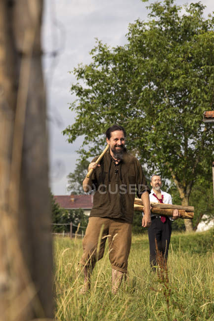 Homme avec hache et homme d'affaires avec pile de bois de chauffage dans le pays — Photo de stock