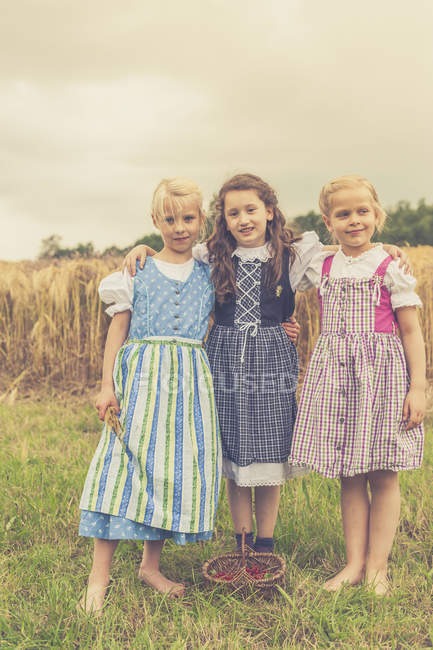 Portrait de trois petites filles portant dirndl sur prairie — Photo de stock