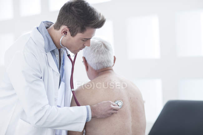 Medico di sesso maschile auscultare paziente in clinica — Foto stock