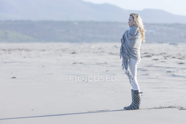 Sudáfrica, Ciudad del Cabo, mujer joven de pie en la playa mirando a la distancia - foto de stock