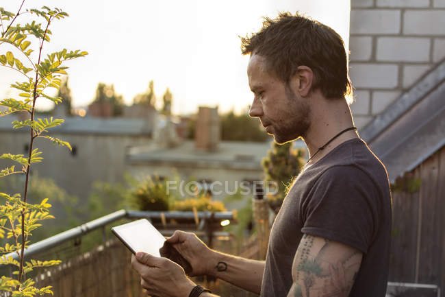 Alemania, Berlín, Hombre maduro en la terraza de la azotea con tableta digital - foto de stock