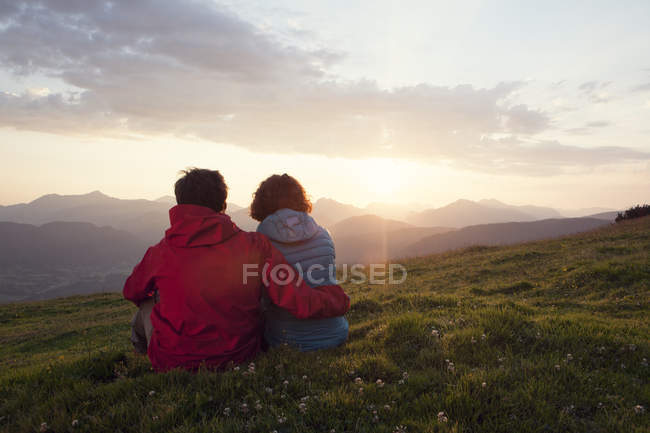 Austria, Tyrol, Unterberghorn, two hikers resting in alpine landscape at sunrise — Stock Photo