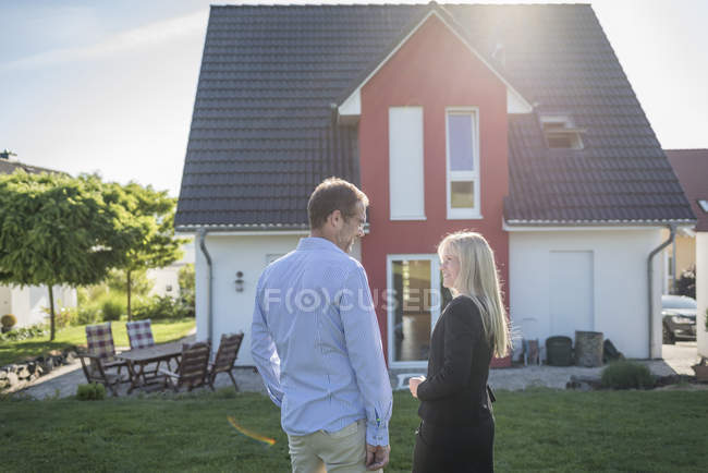 Estate agent and customer standing in front of one-family house — Stock Photo