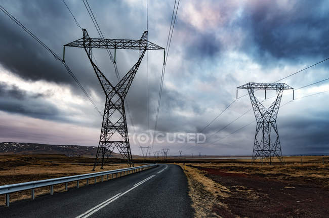 Islandia, Solheimar, autopista 354 y postes de energía bajo cielo nublado - foto de stock