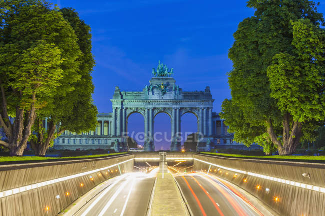 Bélgica, Bruselas, Parc du Cinquantenaire, Triumphal Arch, Avenue John Kennedy por la noche - foto de stock