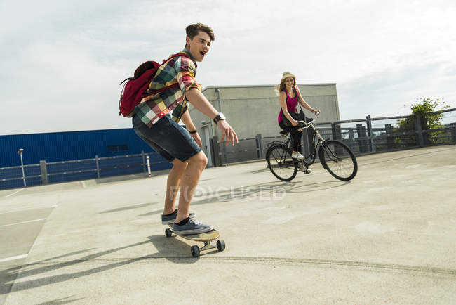 Jovem casal feliz com bicicleta e skate — Fotografia de Stock