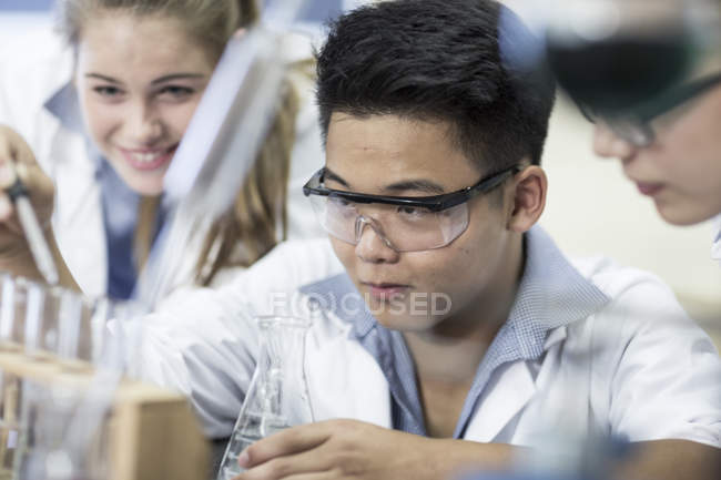 Estudiantes en clase de química pipeteo líquido en tubo de ensayo - foto de stock