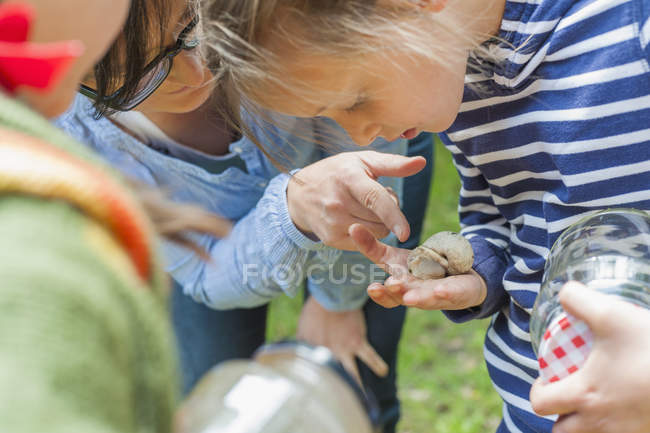 Nahaufnahme von Kindern und Frau beim Anblick von Schnecken in der Hand — Stockfoto