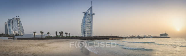 Emiratos Árabes Unidos, Dubai, puesta del sol en Jumeirah Beach con Burj al Arab y Jumeirah Beach Hotel - foto de stock